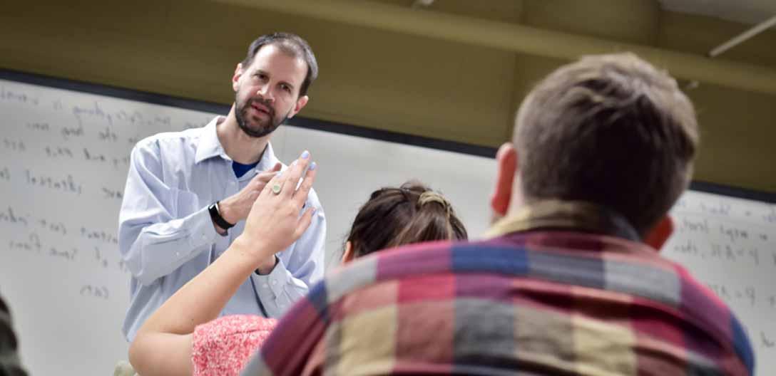 A student raises her hand to ask a question in class